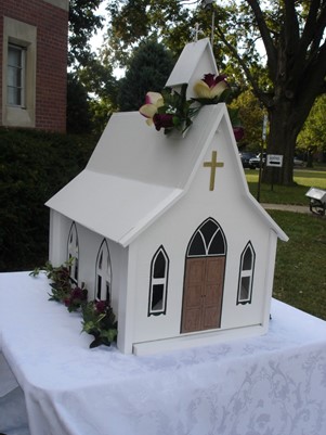 church shaped container on table with white tablecloth.