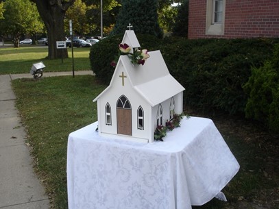 large container shaped like a church on a table with a white tablecloth.